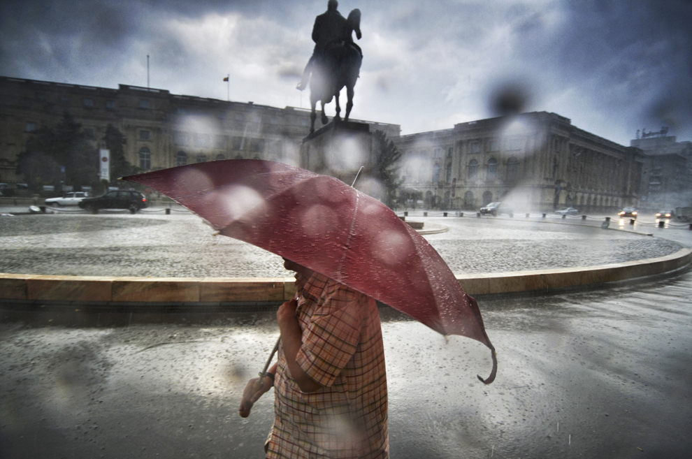 Un bărbat merge prin ploaie, în Bucureşti, vineri, 5 iulie 2013.
