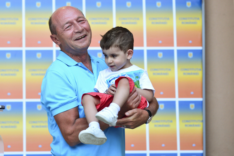 Traian Băsescu, preşedintele suspendat al României, ţine în braţe un copil, în timpul unei declaraţii de presă, în curtea sediului său electoral din Bucureşti, miercuri, 11 iunie 2012. 