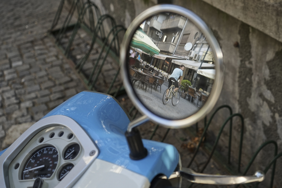 Un bărbat pe bicicletă poate fi văzut în oglida retrovizoare a unui scuter, în Centrul Vechi din Bucureşti, miercuri, 13 august 2014.