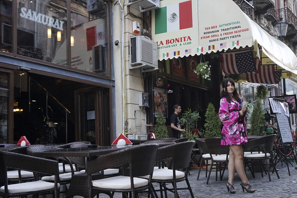 O fată, angajată ca hostess, încearcă să atragă clineţi pentru restaurantul „Samurai”, din Centrul Vechi din Bucureşti, miercuri, 13 august 2014.