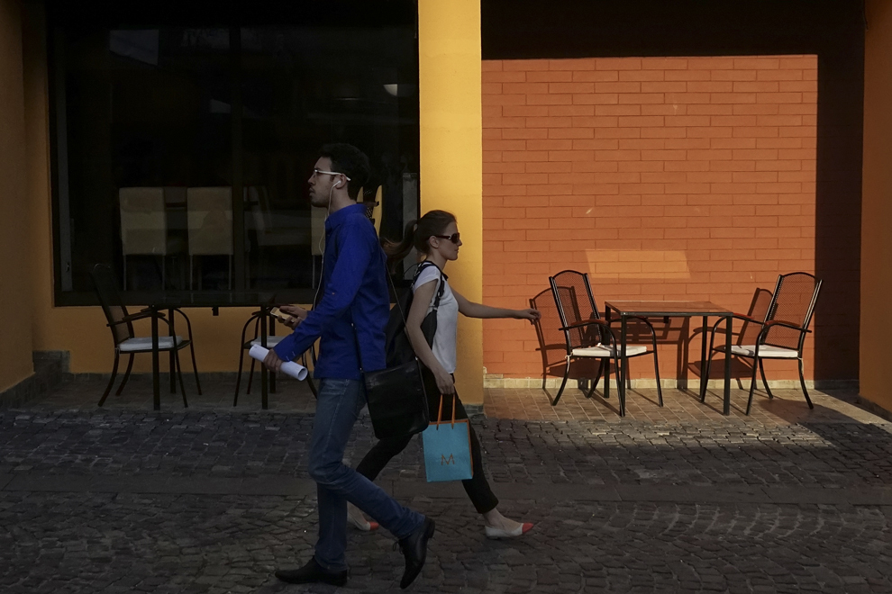 Un bărbat şi o femeie trec unul pe lângă altul pe strada Smârdan din Centrul Vechi din Bucureşti, miercuri, 13 august 2014.