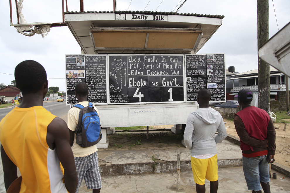Liberieni citesc “The Daily Talk” scris cu cretă pe o tablă aflată pe colţul unei străzi din Monrovia, Liberia, luni, 4 august 2014.
