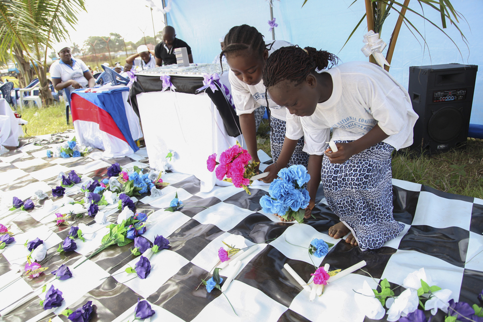 Copii aşează flori în memoria persoanelor decedate în urma contactării virusului Ebola, în Monrovia, Liberia, marţi, 5 august 2014. 