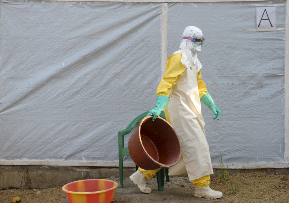 Un specialist medical transportă un recipient de plastic într-un salon de izolare pentru pacienţi, în cadrul centrului pentru victimele virusului Ebola, în Guekedou, Guineea, luni, 31 martie 2014.