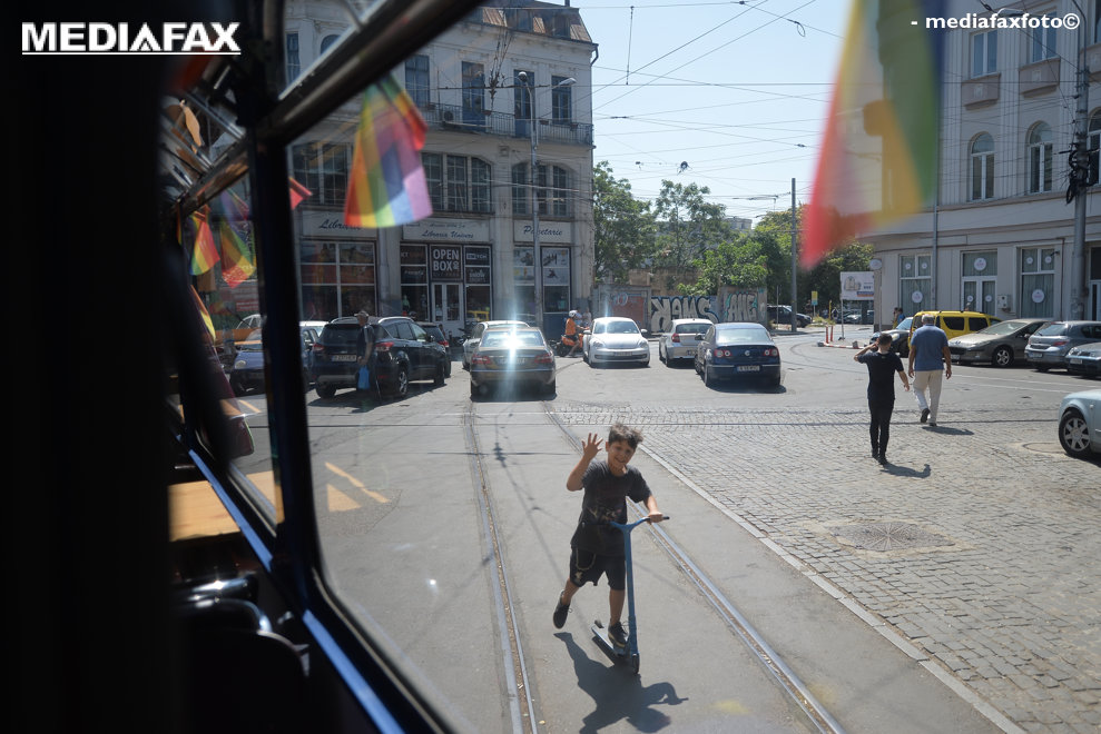 Un copil ce merge pe o trotineta saluta membrii comunitatii LGBTQAI+ in timpul evenimentul "Tramvaiul Rainbow", din cadrul Bucharest Pride 2021, sambata, 14 august 2021. ALEXANDRU DOBRE/ MEDIAFAX FOTO. 
