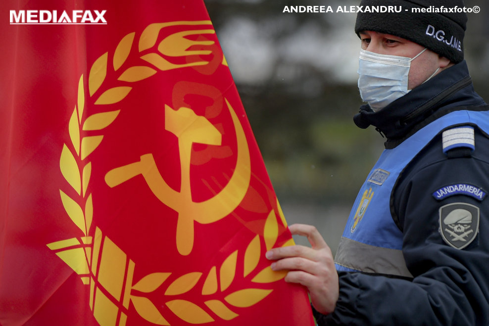 Un jandarm atinge un steag al Partidului Comunist Roman (PCR) in Parcul Garii de Nord din Bucuresti, marti, 16 februarie 2021. ANDREEA ALEXANDRU / MEDIAFAX FOTO