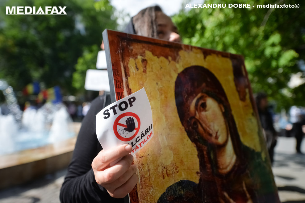 O femeie tine in mana o icoana si un sticker cu mesajul 'Stop incalcarii libertatilor' in timpul unui  protest impotriva masurilor impuse de autoritati in contextul pandemiei de COVID-19, protest organizat in Piata Universitatii din Bucuresti, sambata, 15 mai 2021. ALEXANDRU DOBRE/ MEDIAFAX FOTO.